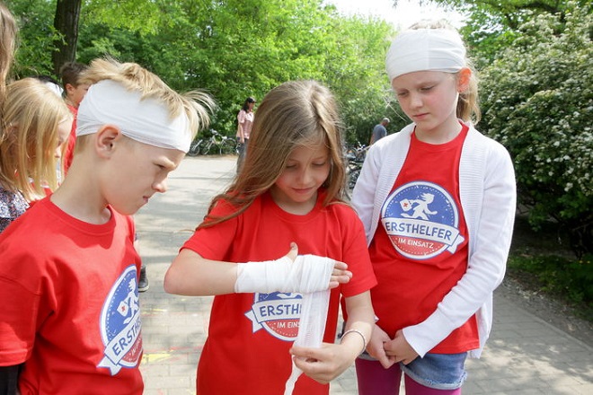 Einen Hand- oder Kopfverband legen unsere Juniorhelfer mit links an. 